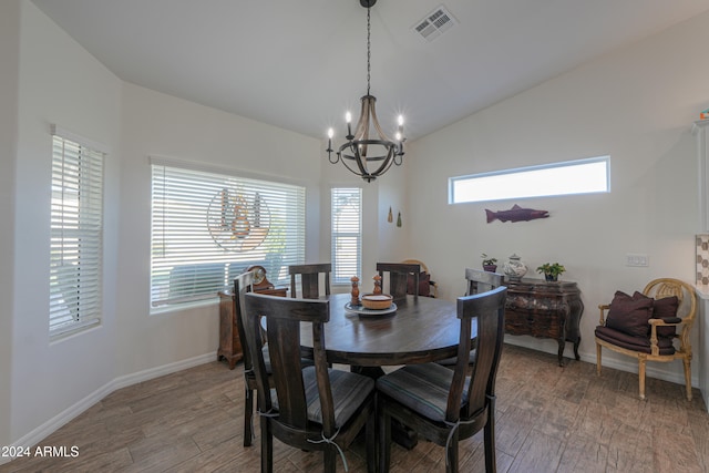 dining room featuring hardwood / wood-style flooring, lofted ceiling, and an inviting chandelier