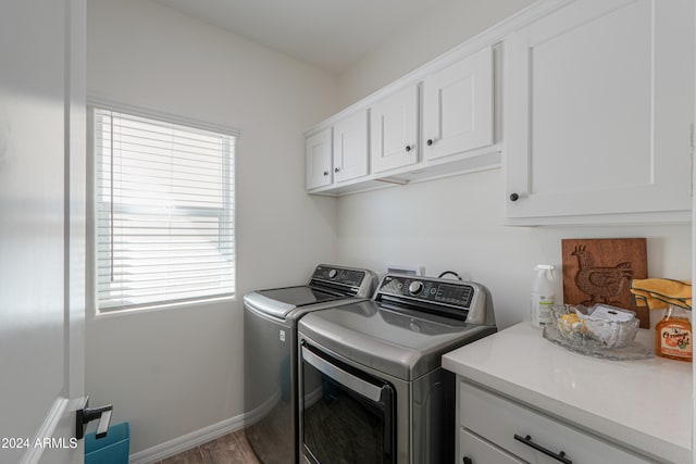 washroom with cabinets, wood-type flooring, and washing machine and clothes dryer