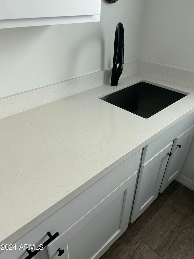 interior details with dark wood-type flooring, white cabinetry, and sink