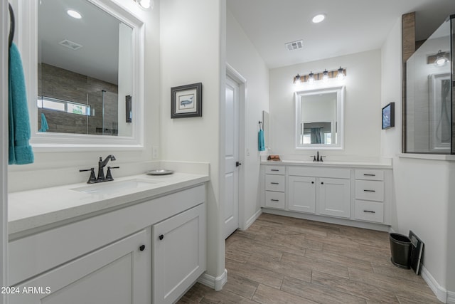 bathroom with vanity, a tile shower, and hardwood / wood-style flooring