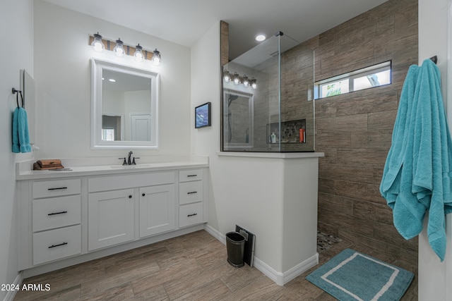 bathroom featuring vanity, wood-type flooring, and tiled shower