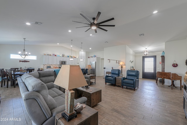 living room with hardwood / wood-style flooring, ceiling fan with notable chandelier, and vaulted ceiling