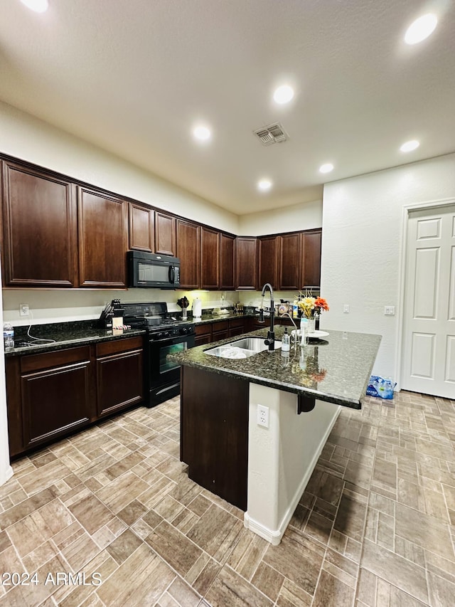 kitchen with sink, a kitchen bar, black appliances, dark stone countertops, and dark brown cabinetry