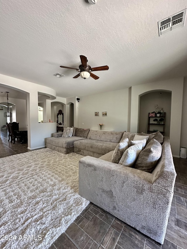 living room featuring ceiling fan, dark tile floors, and a textured ceiling