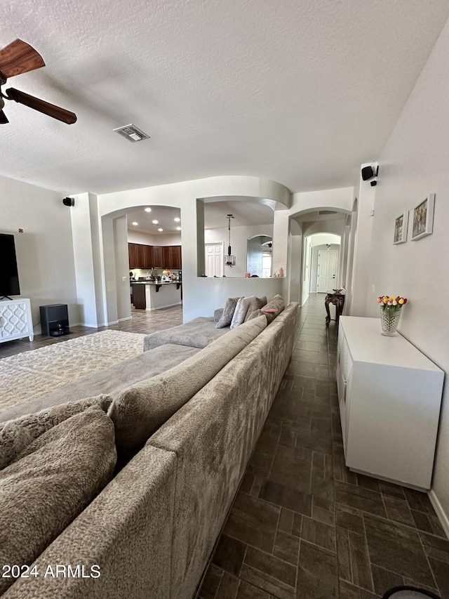 tiled living room with ceiling fan and a textured ceiling