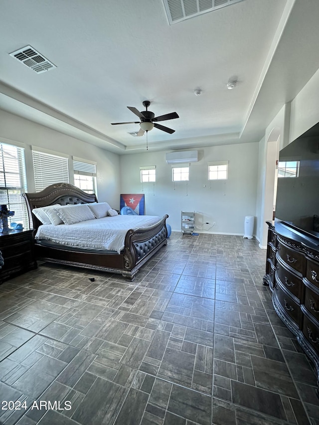 bedroom featuring ceiling fan, dark tile floors, a raised ceiling, and a wall mounted air conditioner