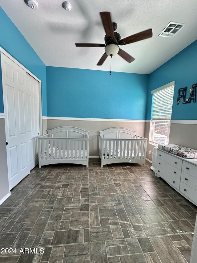 unfurnished bedroom featuring a closet, ceiling fan, a crib, and dark tile floors