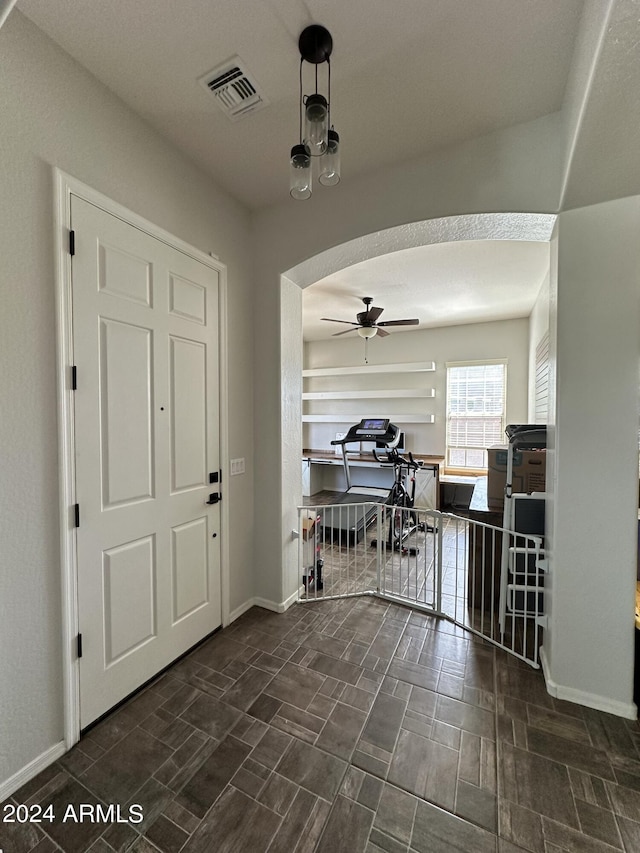 foyer entrance featuring ceiling fan and dark tile floors