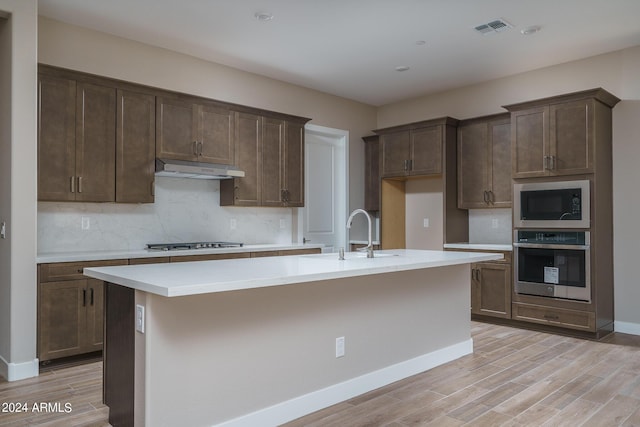 kitchen featuring appliances with stainless steel finishes, sink, a kitchen island with sink, and light hardwood / wood-style floors