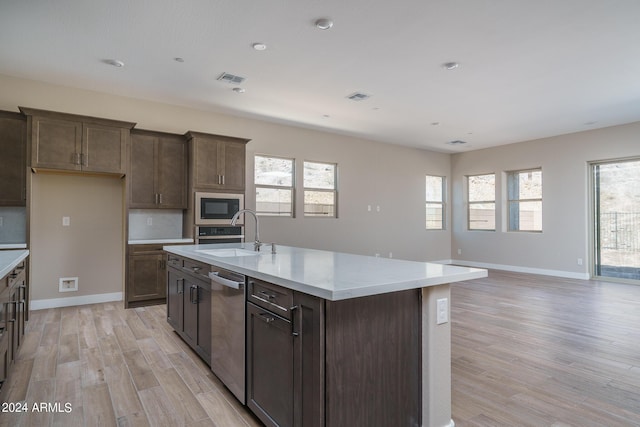 kitchen with sink, light hardwood / wood-style flooring, dishwasher, a kitchen island with sink, and black microwave