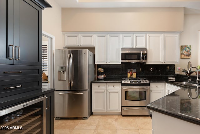 kitchen with wine cooler, sink, dark stone countertops, appliances with stainless steel finishes, and backsplash