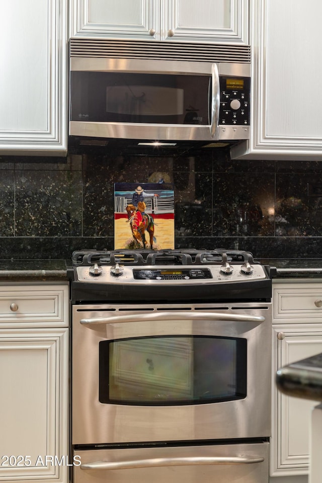 kitchen with tasteful backsplash, stainless steel appliances, dark stone countertops, and white cabinets