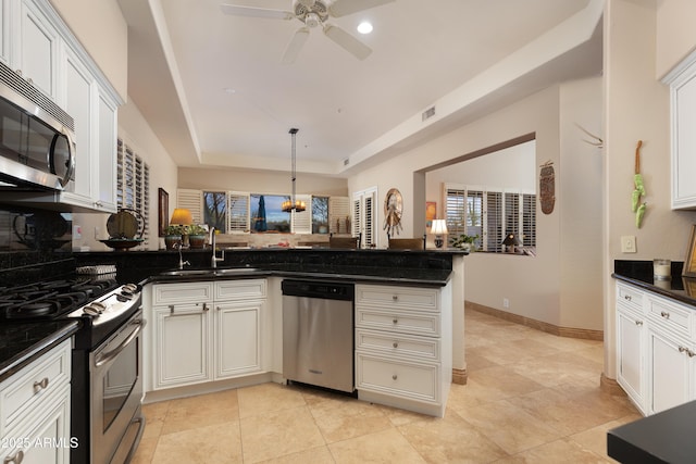 kitchen featuring appliances with stainless steel finishes, kitchen peninsula, sink, white cabinets, and a tray ceiling