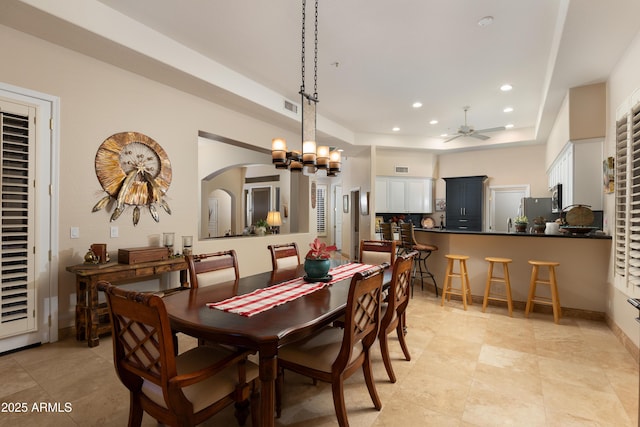 dining room featuring a tray ceiling and ceiling fan with notable chandelier