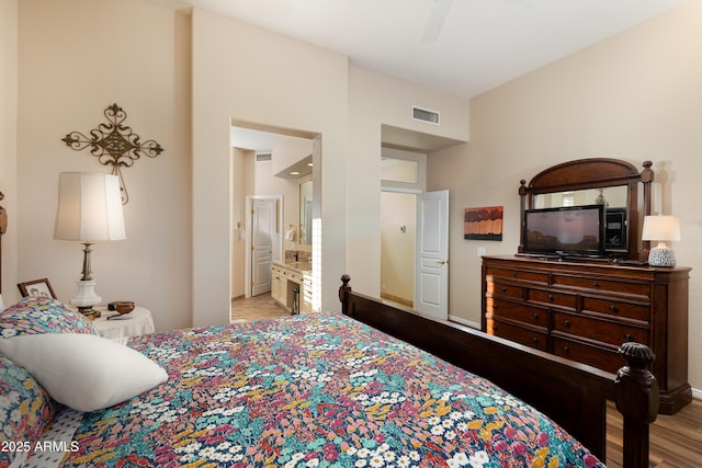 bedroom featuring ceiling fan, ensuite bathroom, and light wood-type flooring