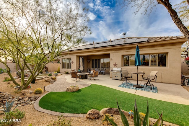 rear view of property with a patio, a yard, and solar panels