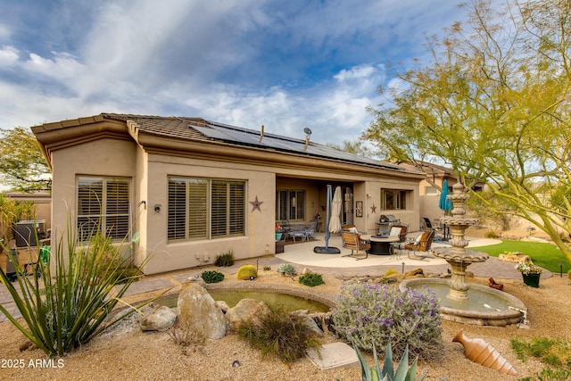 back of house with a patio, a fire pit, and solar panels