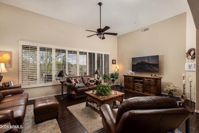 living room featuring a towering ceiling, dark wood-type flooring, and ceiling fan