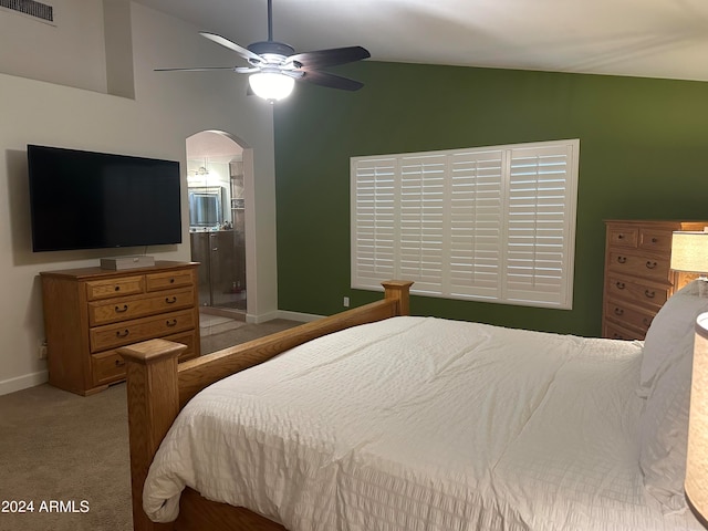 carpeted bedroom with ceiling fan, lofted ceiling, and ensuite bath