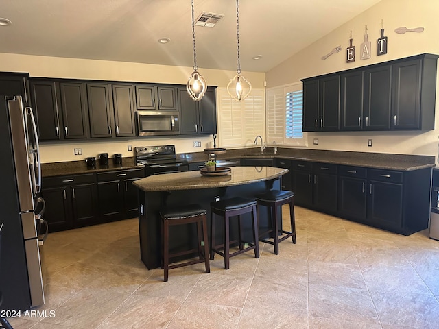 kitchen with a kitchen island, a kitchen breakfast bar, vaulted ceiling, hanging light fixtures, and appliances with stainless steel finishes