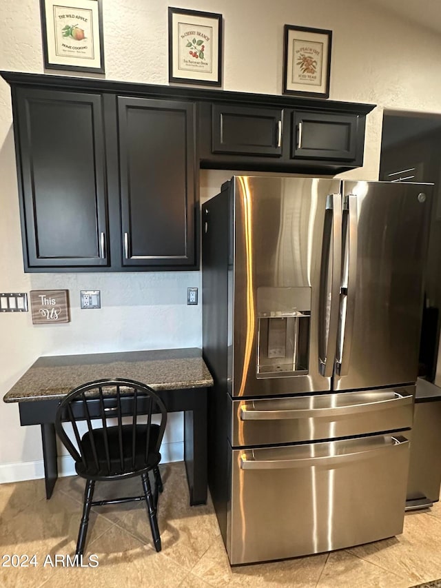 kitchen featuring dark stone countertops and stainless steel fridge