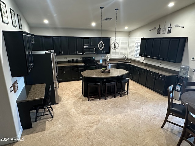 kitchen featuring a kitchen island, stainless steel appliances, sink, hanging light fixtures, and a breakfast bar area