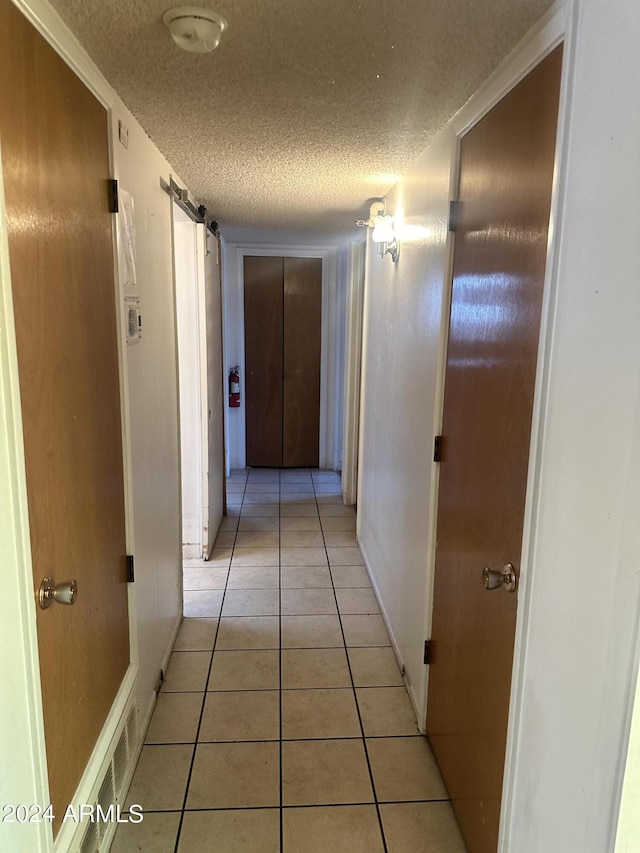 hall featuring light tile patterned floors and a textured ceiling