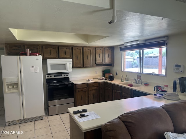 kitchen with light tile patterned floors, white appliances, dark brown cabinets, a textured ceiling, and sink