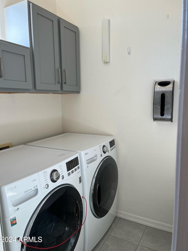 washroom featuring washing machine and dryer, cabinets, and light tile patterned floors