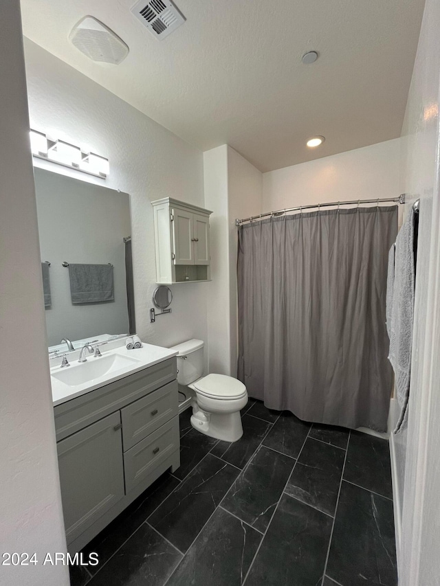 bathroom with walk in shower, vanity, and toilet