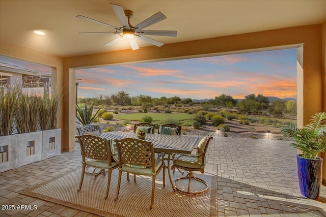 patio terrace at dusk with a ceiling fan and outdoor dining space