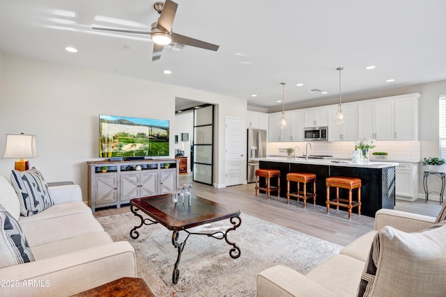 living room featuring ceiling fan, light wood finished floors, and recessed lighting