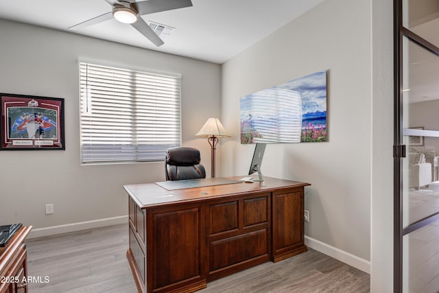 office featuring a ceiling fan, light wood-style flooring, and baseboards