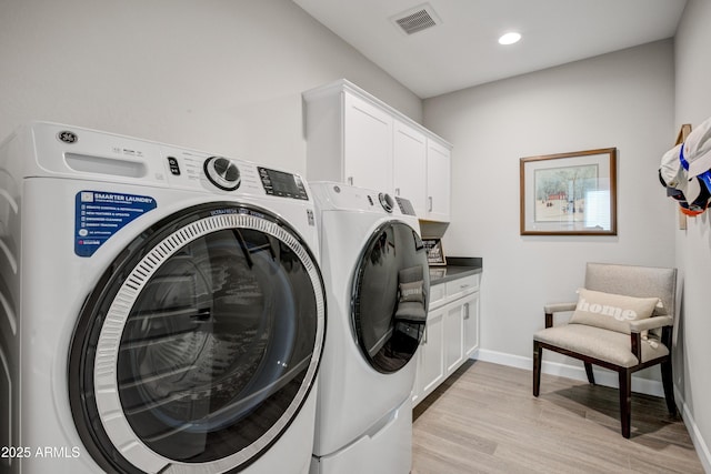 clothes washing area featuring washing machine and clothes dryer, cabinet space, light wood-type flooring, recessed lighting, and baseboards