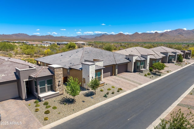 view of front of house featuring stone siding, decorative driveway, an attached garage, and a mountain view