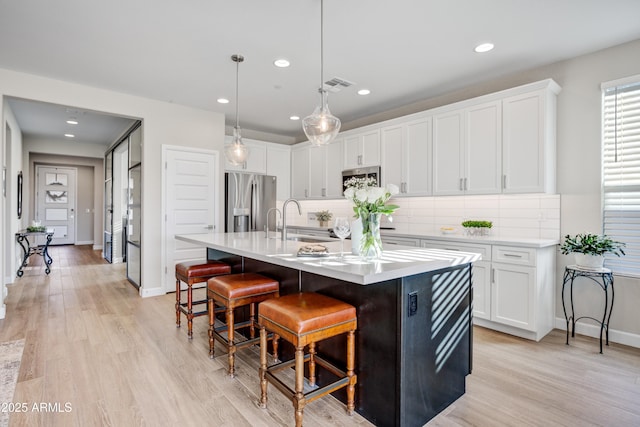 kitchen with appliances with stainless steel finishes, a kitchen bar, white cabinets, decorative backsplash, and recessed lighting