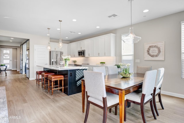 dining room featuring baseboards, light wood finished floors, and recessed lighting