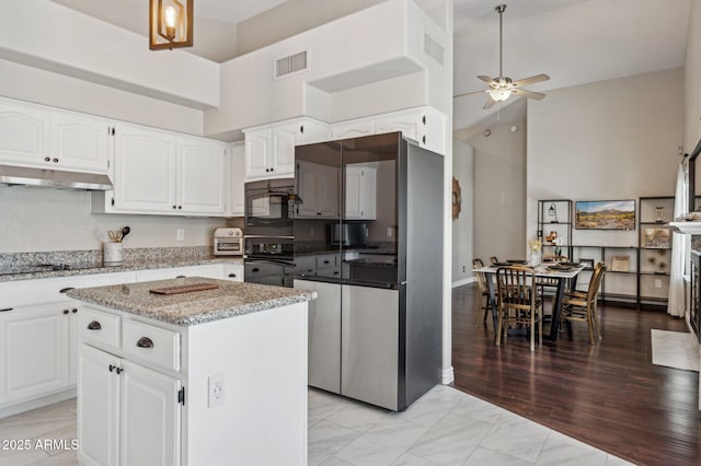 kitchen featuring black appliances, a kitchen island, visible vents, and white cabinets