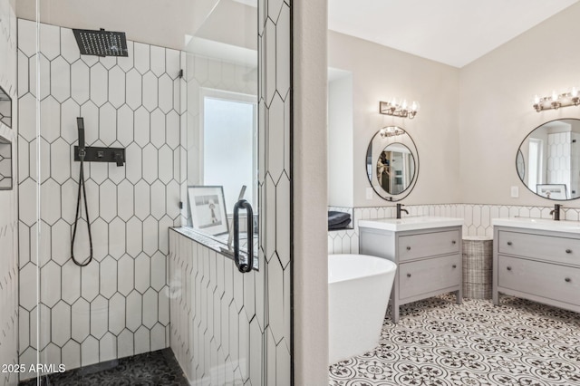 full bathroom featuring a wainscoted wall, two vanities, tile walls, tile patterned floors, and walk in shower