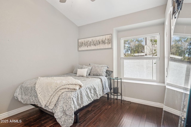 bedroom with baseboards, vaulted ceiling, and dark wood-style flooring