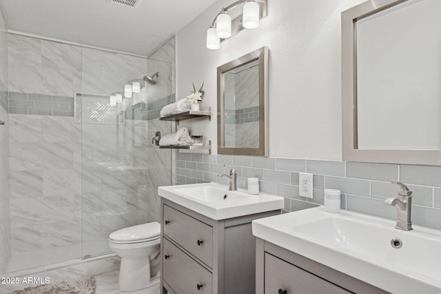 full bath featuring marble finish floor, two vanities, a sink, and a shower stall