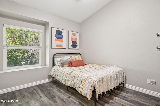 bedroom with lofted ceiling, dark wood-style flooring, and baseboards