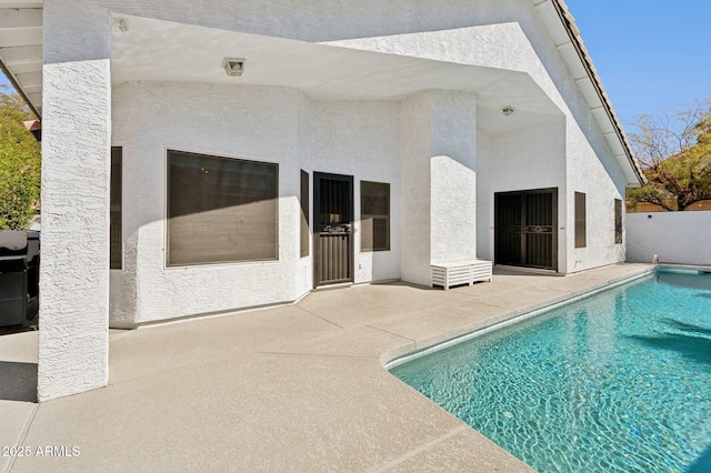 back of property with a patio area, fence, an outdoor pool, and stucco siding