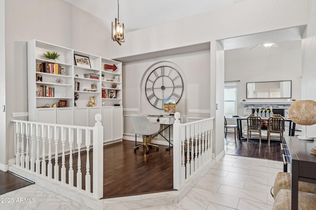 office area with a fireplace, wood finished floors, and an inviting chandelier