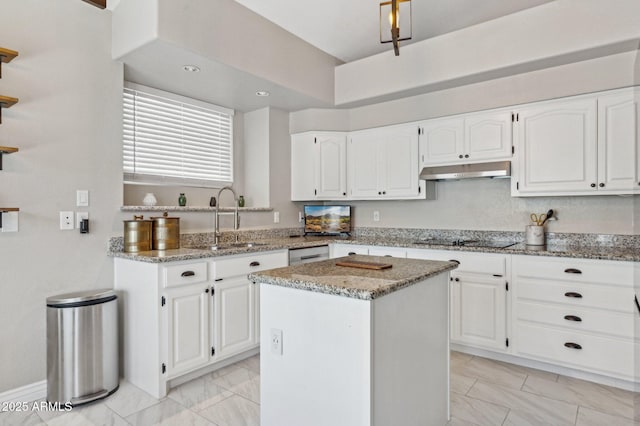 kitchen with under cabinet range hood, a kitchen island, stone counters, and white cabinets