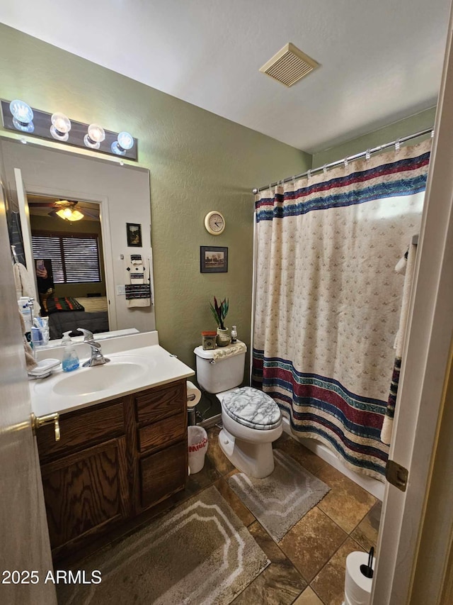 bathroom with walk in shower, vanity, and toilet