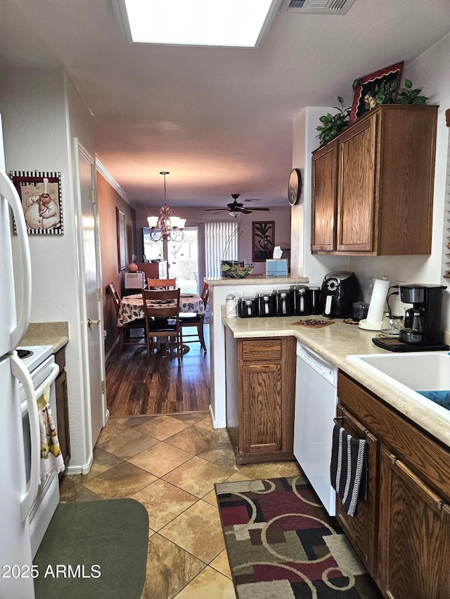 kitchen with white appliances, dark tile patterned floors, ceiling fan with notable chandelier, decorative light fixtures, and kitchen peninsula