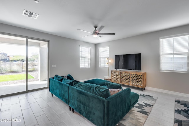 living area featuring baseboards, a ceiling fan, and visible vents