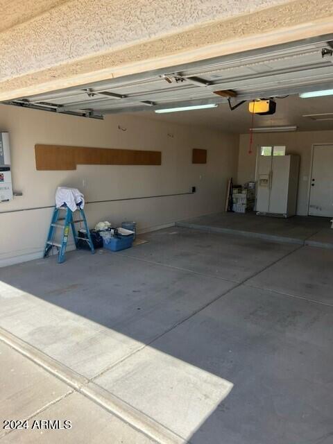 garage with white refrigerator with ice dispenser and a garage door opener