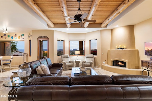 living room featuring beamed ceiling, ceiling fan, a large fireplace, and wood ceiling